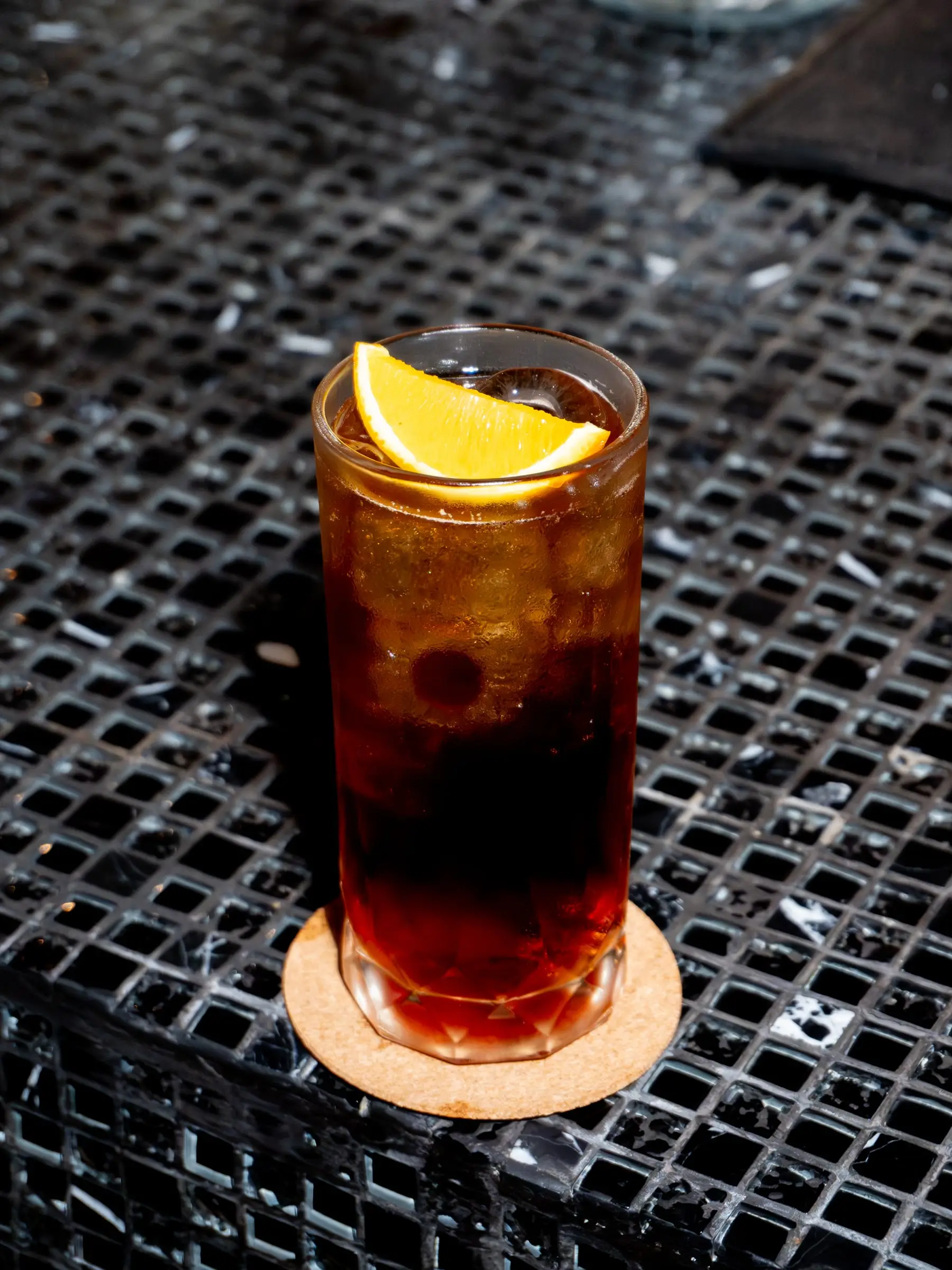 Iced drink with an orange slice on a dark mosaic table
