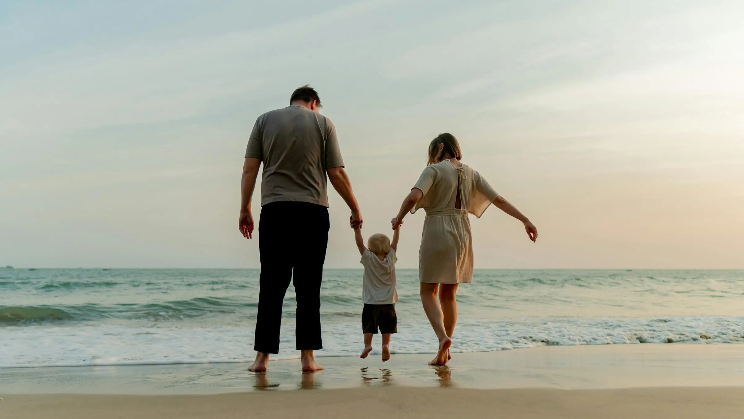 Family walking hand in hand towards the sea