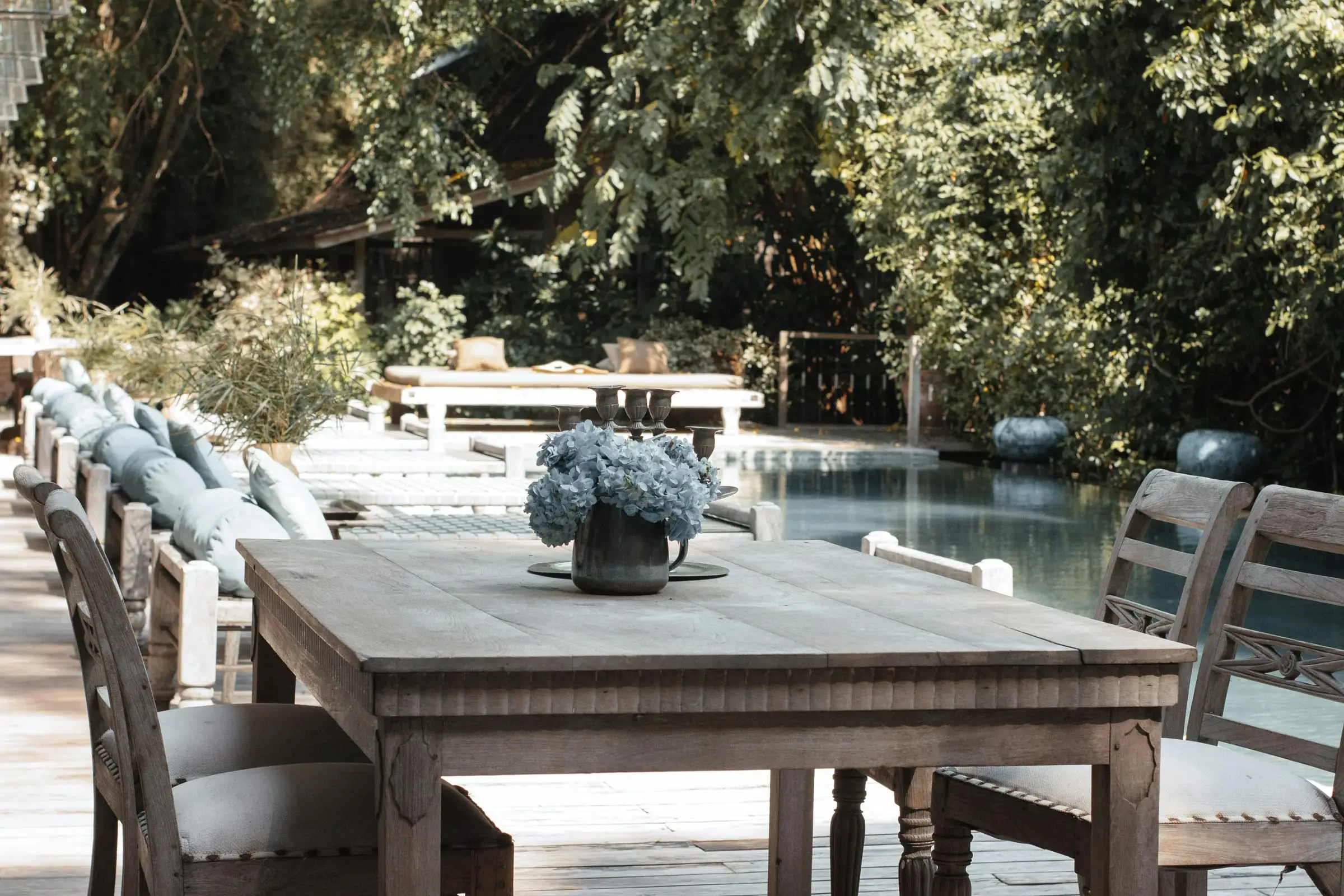 Wooden dining table beside a tropical villa pool