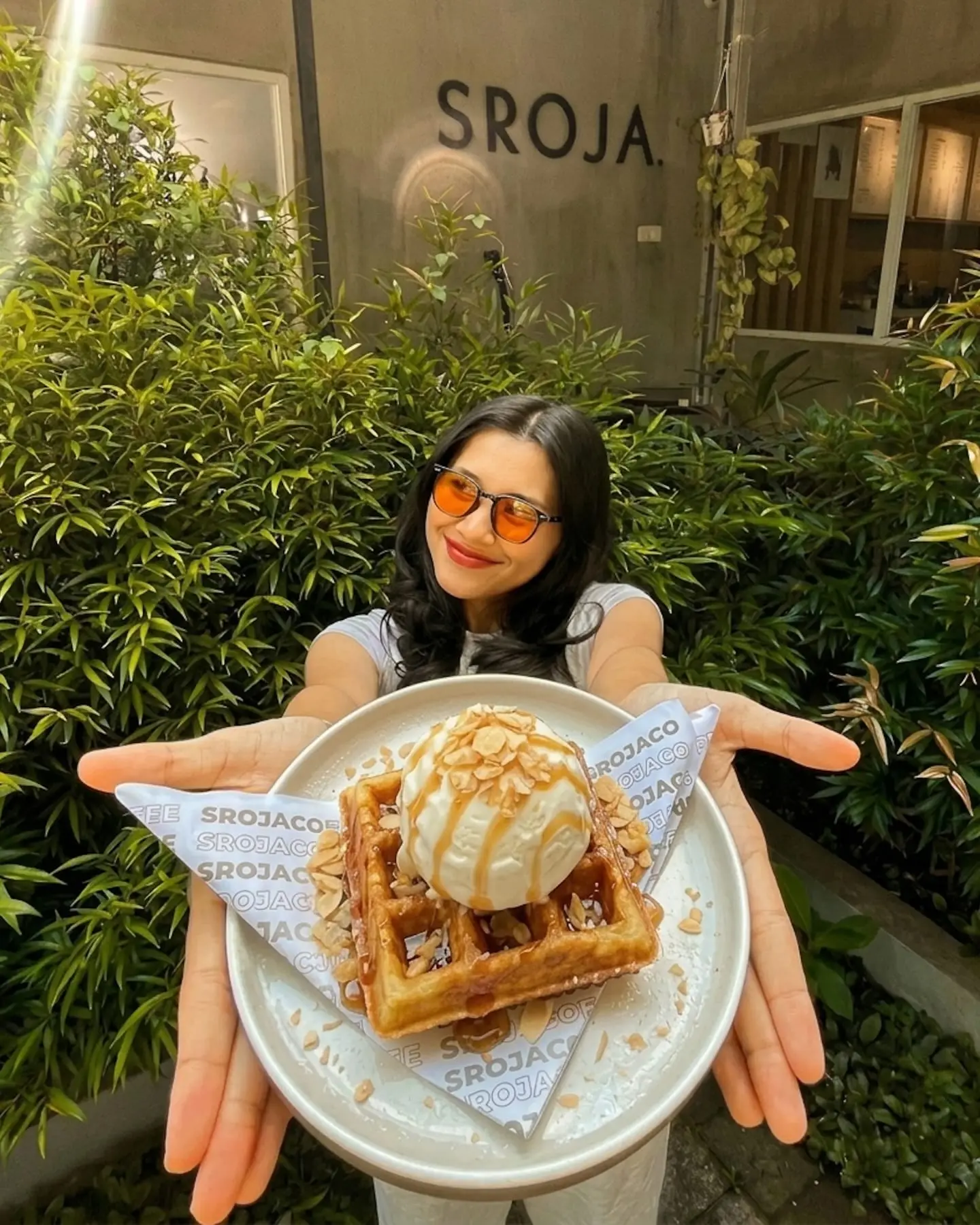 Guest holding out a waffle with ice cream in front of a café